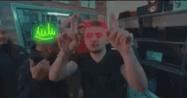 a group of people are dancing in a room with a neon sign that says ' i love you ' on it