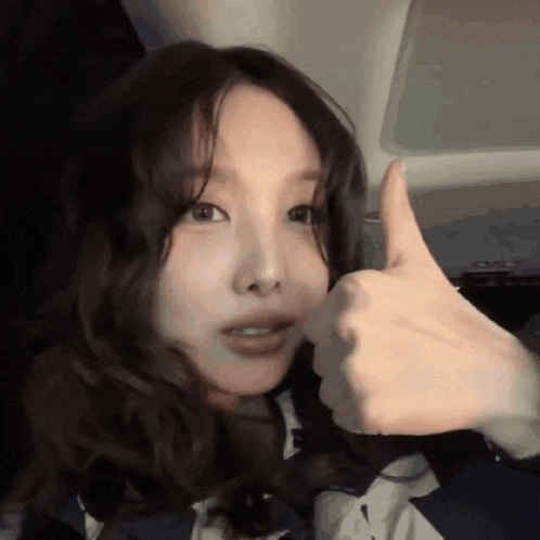 a woman in a car is giving a thumbs up