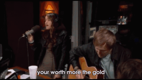 a woman singing into a microphone next to a man playing a guitar with the words your worth more the gold above them