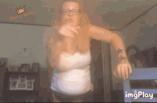 a woman in a white tank top is dancing in front of a sign that says betty boop