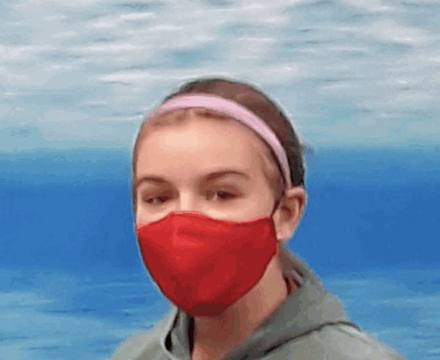a young girl wearing a red face mask with a pink headband