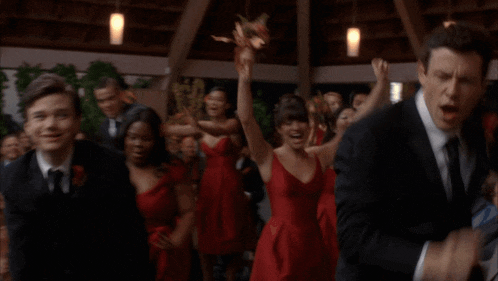 a group of people are dancing in a room with an exit sign