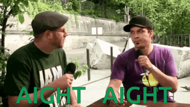 two men are sitting at a table with the words " aight aight " in green