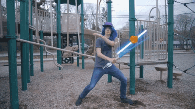 a man in a blue hat is holding a light saber in a playground
