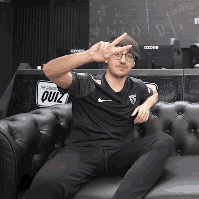 a man sits on a couch in front of a sign that says quiz