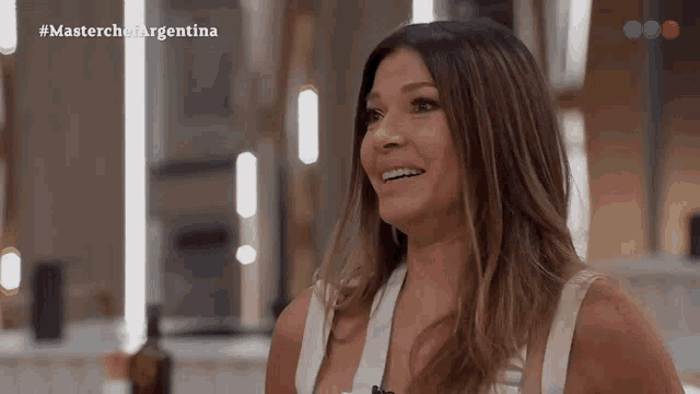a woman is smiling in front of a screen that says masterchefargentina