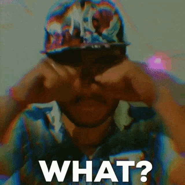 a man wearing a ny hat is covering his eyes with his hands and the word what is visible in the foreground