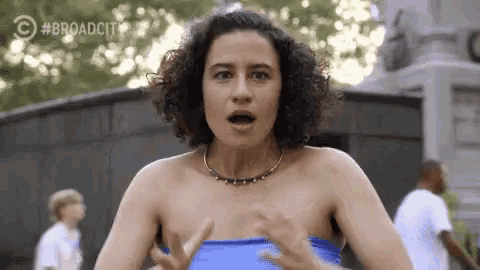 a woman in a blue top is making a surprised face with her mouth open .