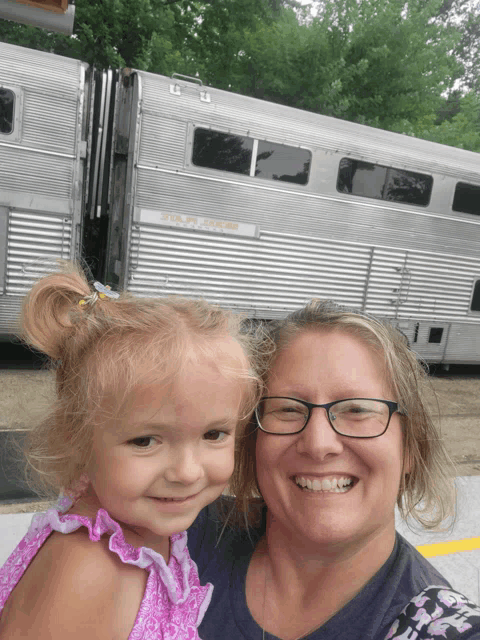 a woman holds a little girl in front of a horse trailer that says ' u.s. army ' on it
