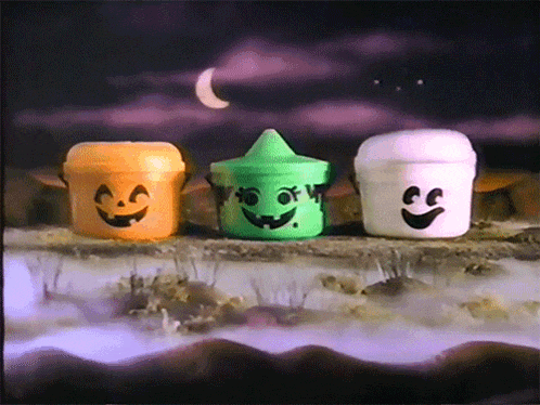 three halloween buckets with faces painted on them are sitting on a rock
