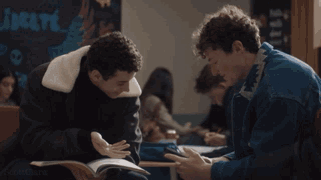 two young men are sitting at a table in front of a chalkboard that says " incite " on it