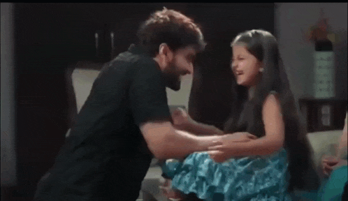 a man is holding a little girl in his arms and they are laughing together .