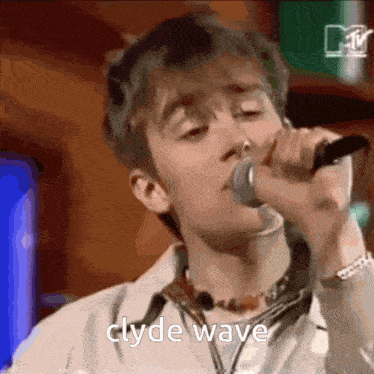 a close up of a man singing into a microphone with the words clyde wave above him .