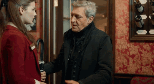 a man holding an umbrella is talking to a woman in a red jacket
