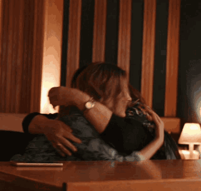 two women hugging each other in a room with striped walls