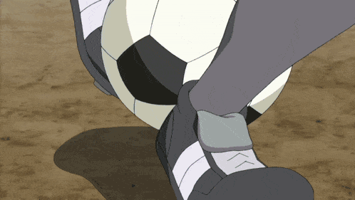 a person is kicking a soccer ball with a glove on