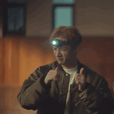 a man wearing a bomber jacket has a flashlight on his head and a t-shirt that says crab