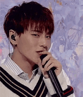 a young man with red hair is singing into a microphone while wearing earbuds