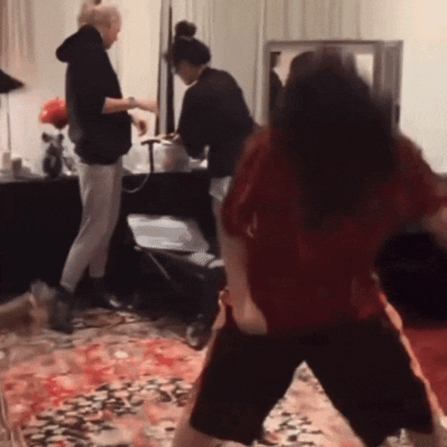 a woman in a red shirt is dancing in front of a mirror
