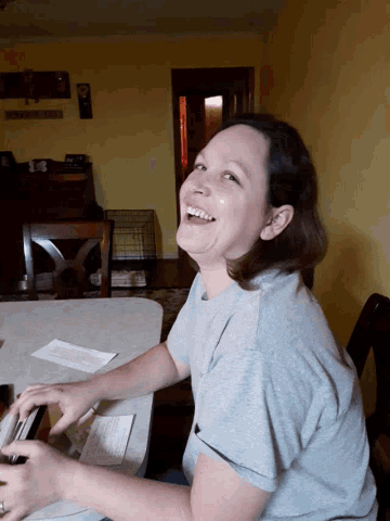 a woman is smiling while sitting at a table with papers