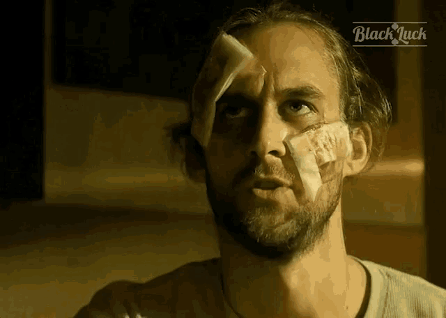 a man with a bandage on his face has the word black luck on the bottom left