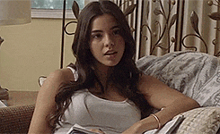 a young woman is sitting on a couch reading a book .