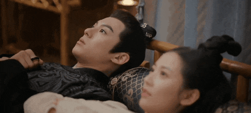 a man and a woman are laying on a bed and the man has a ring on his finger .
