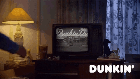 a dunkin ' coffee cup sits on a table in front of a tv