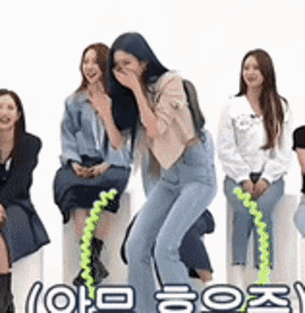 a group of women are sitting on a white wall and laughing .