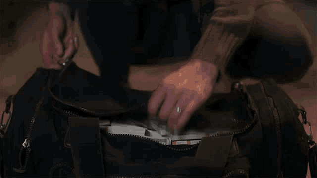 a person is putting money in a bag that has a zipper