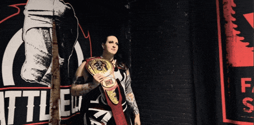 a female wrestler stands in front of a sign that says " battle "