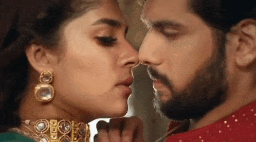 a man and a woman are kissing with their noses together .