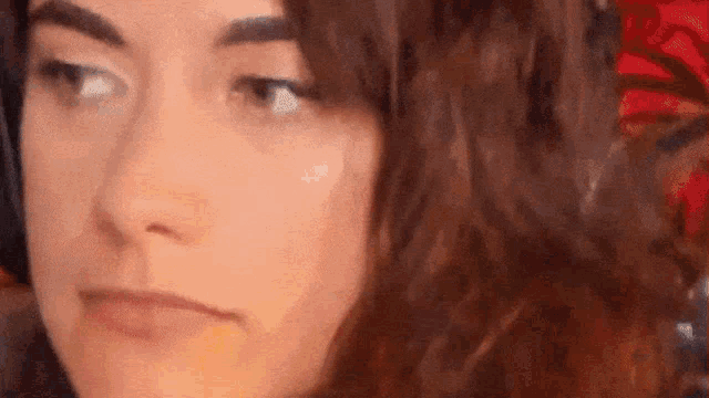 a close up of a woman 's face with curly hair making a funny face