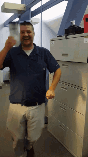 a man in a blue shirt is standing in front of a cabinet