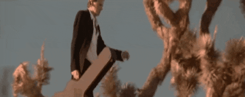 a man in a suit and tie is standing on a skateboard in front of a cloud of smoke .