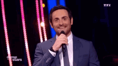 a man in a suit and tie is holding a microphone .