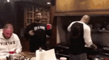 a man wearing a hoodie that says views is standing in a kitchen