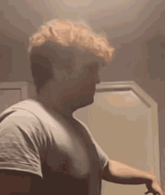 a man in a white shirt is standing in front of a white door .