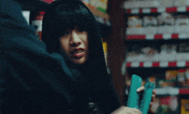 a woman in a black hooded sweatshirt is holding a blue item