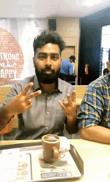 a man with a beard is sitting at a table with a cup of coffee in front of him