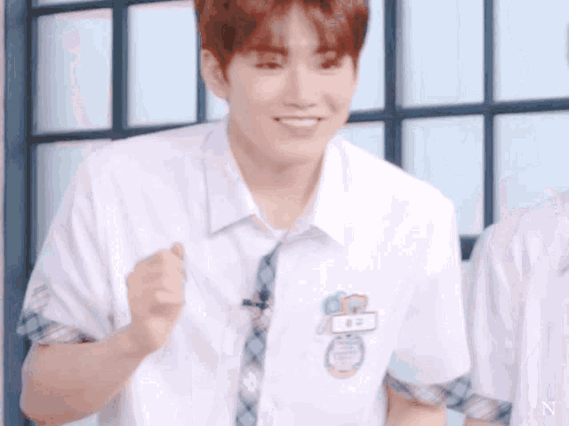 a young man wearing a white shirt and tie with the letter n on the front