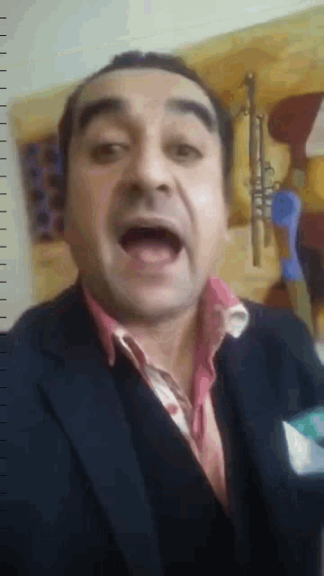 a man wearing a suit and a pink shirt is making a funny face .