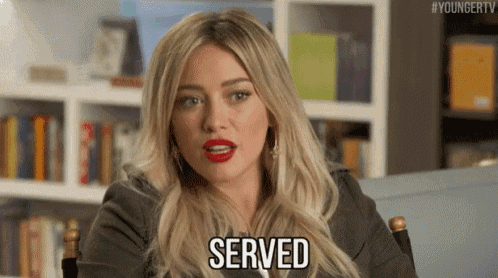 a woman with blonde hair and red lipstick is sitting in a chair and saying served .