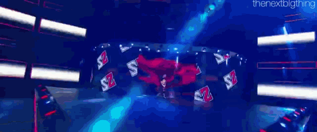 a man in a black shirt is dancing on a stage in front of a red wall with the number 2 on it .