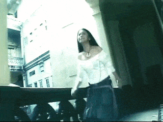 a woman in a white off the shoulder top is walking down a balcony