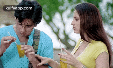 a man and a woman are sitting next to each other drinking juice through straws .