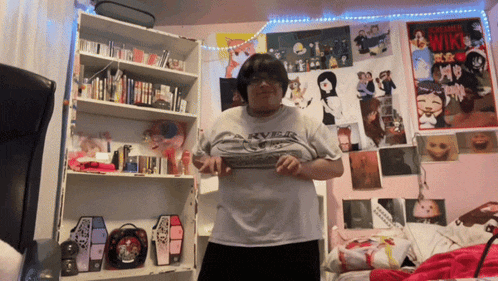 a woman in a room with posters on the wall including one for screaming witches
