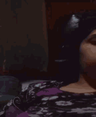 a woman in a purple and black floral shirt is sleeping on a bed