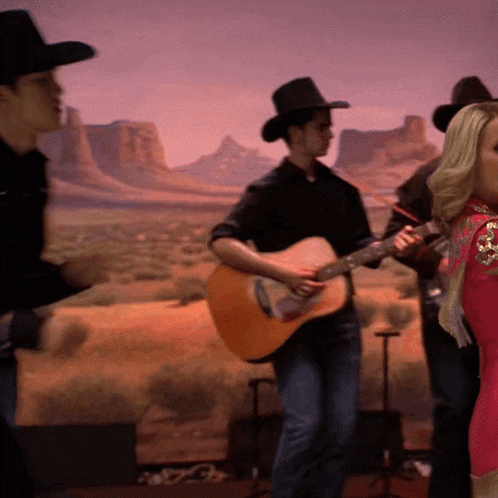 a man in a cowboy hat playing a guitar