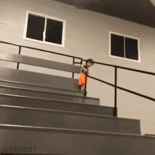 a young boy is walking up a set of stairs with a railing and a window in the background